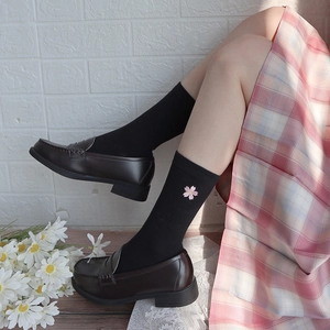 Detail of pink cherry blossom embroidery on black mid-calf socks with leather loafers