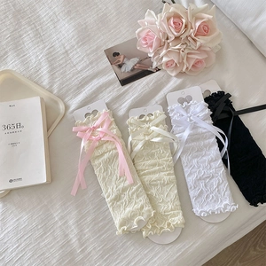 Close-up of lolita lace leg warmers with ribbon bows in pink, beige, white, and black colors