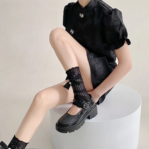 Détail de jambières en dentelle noire avec nœuds et chaussures Mary Jane à plateforme