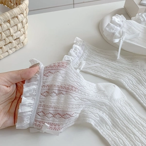 Detailed view of white lace socks featuring ribbon bows and ruffled mesh texture