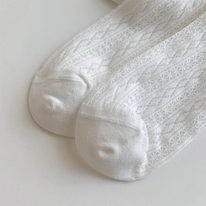 Close-up of white lace mesh socks with hollow heart patterns and intricate knit details