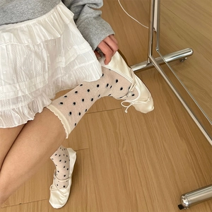 Détail de ballerines crème avec rubans et chaussettes blanches en résille à pois noirs