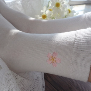 Close-up of white cotton socks featuring delicate pink cherry blossom floral embroidery