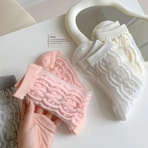 Detail of floral lace mesh socks in pastel colors with elegant embroidery on white table