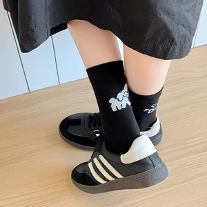 Détail de chaussettes mi-mollet en coton avec broderie chien blanc et baskets de sport
