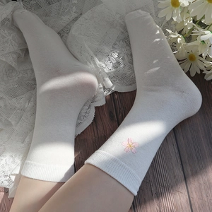 Close-up of white mid-calf socks featuring delicate pink cherry blossom embroidery