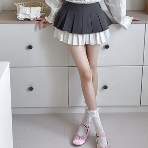 Detail view of double-layer pleated mini skirt with grey and white patchwork layers