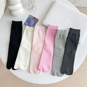 Vertical rib knit split-toe socks in six colors displayed on a white table set