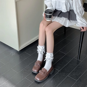 Detail of white mid-calf socks with double bows paired with brown bow loafers