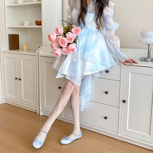Détail de collants en dentelle blanche avec nœuds et robe à volants bleu clair