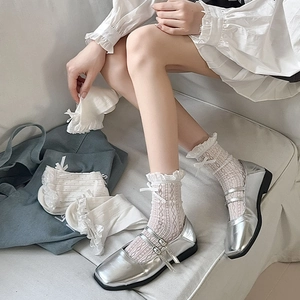 Detail of white lace socks with bow ribbons and mesh heart patterns with Mary Jane shoes