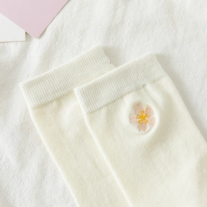 Close-up of pink cherry blossom embroidery on ribbed white cotton knee-high socks