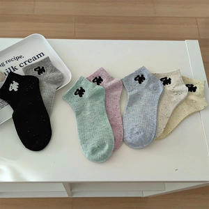 Detail of colorful confetti knit socks featuring cute black puppy embroidery in seven colors