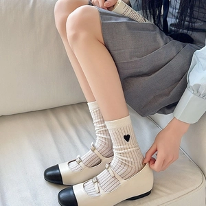 Detail of white striped crew socks with black heart embroidery and Mary Jane shoes