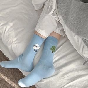 Détail de chaussettes en coton bleu clair avec broderie lapin et arbre et bords côtelés