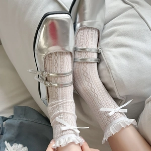 Detailed close-up of white lace socks with bows and silver Mary Jane shoes in retro style