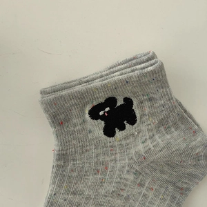 Detailed close-up of grey mélange knit sock featuring cute black puppy embroidery and speckled yarn