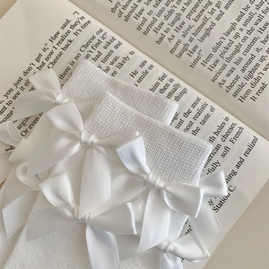 Close-up of white Lolita socks with ribbon bows on vintage English book background