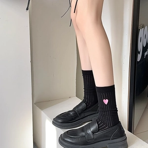 Detail of white vertical striped socks featuring a cute pink heart embroidery on the side