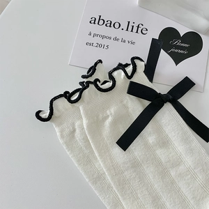 Detailed view of white mesh socks with black ruffled edges and delicate silk ribbon bows