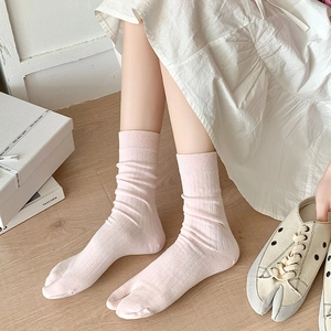 Detail of light pink ribbed tabi socks paired with matching split-toe canvas shoes