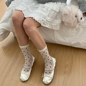 Détail de chaussettes beiges à pois avec bords ondulés et ballerines blanches