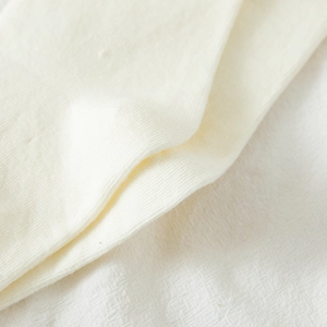 Macro detail of high quality off-white ribbed knit fabric showing soft texture and pattern
