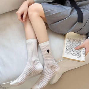 Close-up of white ribbed crew socks with delicate black heart embroidery on the side