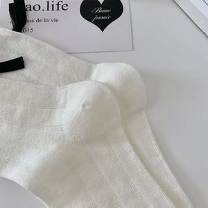 Detailed close-up of white ribbed socks with elegant black silk ribbons and bow detail