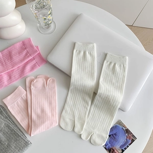 Close-up of ribbed knit tabi socks in white pink and grey on a cozy home desk