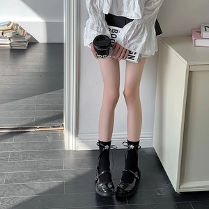 Détail de chaussettes mi-mollet blanches avec nœuds noirs et pendentifs étoile argent