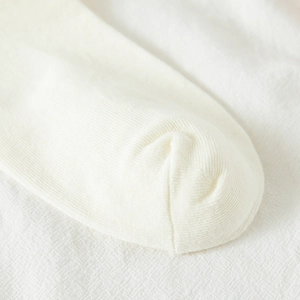 Close-up of white rib-knit fabric detail showing premium texture and fine stitching