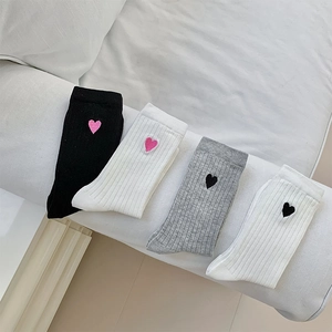 Detail of four pairs of ribbed socks in black, white, and grey with heart embroidery