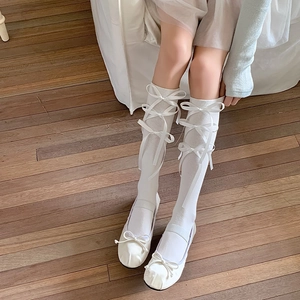 Detail van witte kniekousen met zijden strikjes in Japanse Lolita-stijl