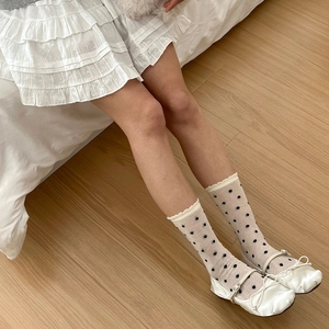 Détail de ballerines Mary Jane blanches avec nœud et chaussettes en résille à pois noirs