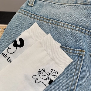 Gros plan de chaussettes en coton blanc avec illustration de chat noir et bord côtelé