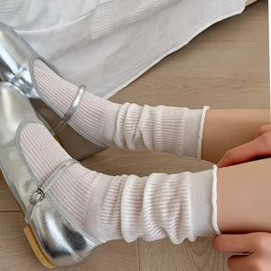 Close-up of white ribbed crew socks with rolled edges paired with silver Mary Jane shoes