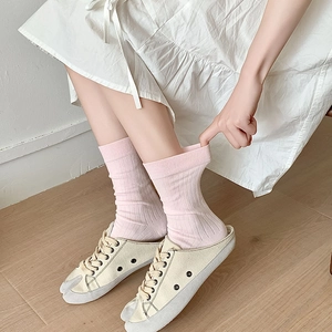Detailed view of pink ribbed tabi socks paired with split-toe mules on a wood floor
