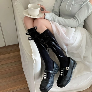 Detail van zwarte Lolita kniekousen met satijnen strikken en parel Mary Jane schoenen
