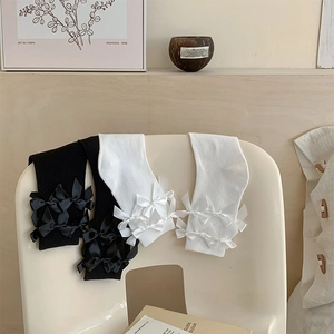 Detail of sweet Lolita knit high socks with layered bows displayed on a white chair