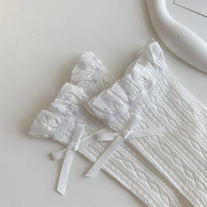 Close-up of white lace socks with ribbon bow and hollow-out mesh texture detail