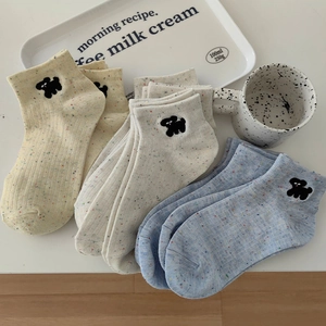 Detail shot of knitted socks with colorful speckles and cute cartoon puppy embroidery
