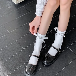 Détail de chaussettes blanches avec nœuds en satin, étoiles et chaussures Mary Jane noires