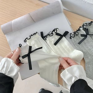 Close-up of white and grey ribbed socks with black ruffle edges and ribbon bows