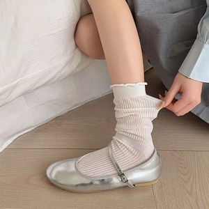 Close-up of white ruffled crew socks paired with silver metallic Mary Jane shoes