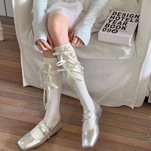 Detail van witte Lolita kousen met strikken gecombineerd met zilveren Mary Jane schoenen