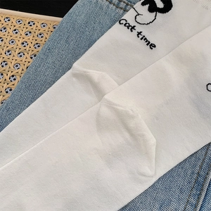 Détail de chaussettes en coton blanc avec texte Cat Time et motifs sur fond denim
