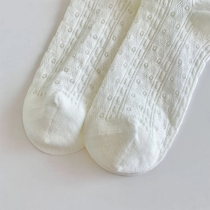 Detailed macro view of white hollow knit socks with delicate polka dot texture
