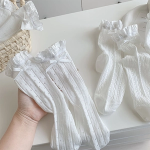 Detail of white lace socks with ribbon bows and hollow heart mesh in a woven basket