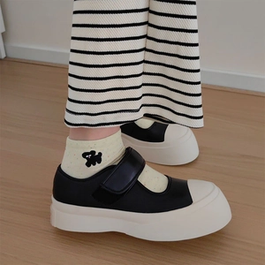 Close-up of black leather Mary Jane platform sneakers with cute embroidered socks